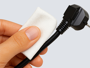 Eine Hand hält ein schwarzes Elektrokabel und reinigt es mit einem weißen Tuch.