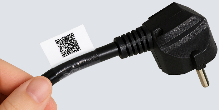 Ein schwarzes Elektrokabel mit einem Stecker an einem Ende, das von einer Hand gehalten wird. An dem Kabel ist ein weißes Hybrid-Etikett mit einem QR-Code angebracht.