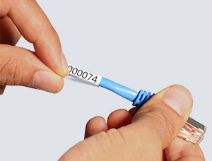 Zwei Hände bringen den selbstlaminierenden Kabelmarkierer auf ein blaues Ethernet-Kabel auf. Das Etikett hat die gedruckte Nummer „000074“ auf seinem weißen Abschnitt und der transparente Laminatbereich wird straff um das Kabel gewickelt.
