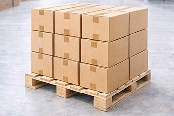 Mehrere verschlossene Kartons stehen nach dem Verpackungsprozess gestapelt auf einer Palette und sind versandfertig vorbereitet.