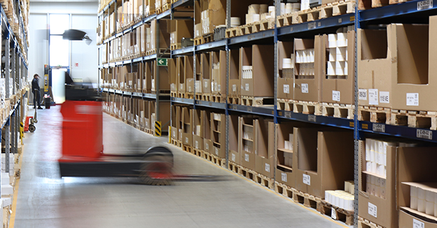 Stapler transportiert Ware in einem großen Etikettenlager mit hohen Regalen.